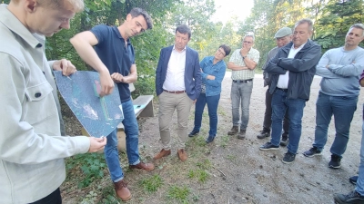 Erik Vorlaufer (links) und Daniel Koglin erläuterten den Stadträten im Schussbachwald bei Haaghof die Pläne für eine Bürger-Windkraftanlage. (Foto: Katrin Merklein)