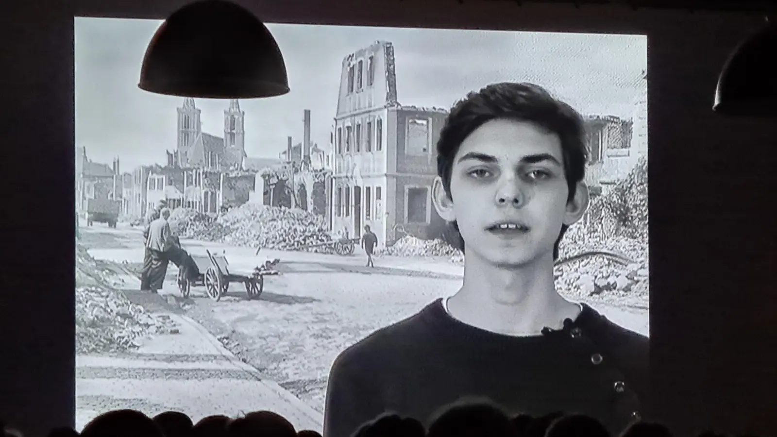 Viele Menschen schauten sich den Film „Ein Tag, der zur Nacht wurde – Rothenburg in Flammen“ an. Das Bild zeigt eine Szene mit einer historischen Aufnahme von der zerstörten Stadt. Bei dem Jugendlichen im Vordergrund handelt es sich um Jan Heinig, der 2015 als Schüler an der Filmproduktion mitgewirkt hatte. (Foto: Margit Schwandt)