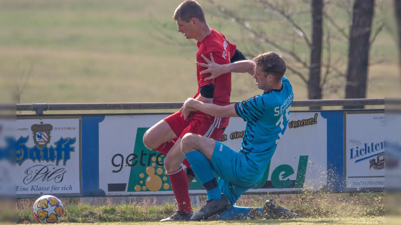 Das Gras spritzt: Der Mosbacher Tim Dollinger bremst Kevin Hofmann vom FC Dombühl. (Foto: Markus Zahn)