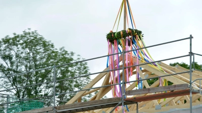 Richtkranz auf einem neu gebautem Haus. Richtfest auf einer Lückenbebauung. An einem neu gebauten Wohnhaus im Speckgürtel von Leipzig hängt ein Richtkranz im rohbaufertigen Dachstuhl. (Foto: Volkmar Heinz/dpa-Zentralbild/dpa-tmn)