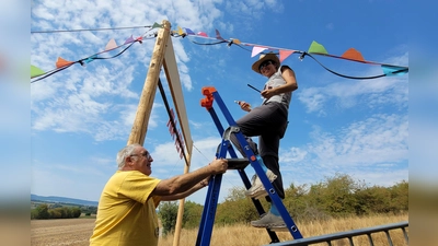 Eleni Martin aus dem P-Seminar ist zugleich Helferin auf dem Festival, genauso wie ihr Vater Uwe Martin. Gemeinsam haben sie die bunten Wimpel und die Lichterkette an den Seiten-Seilen des Torbogens montiert. (Foto: Nina Daebel)