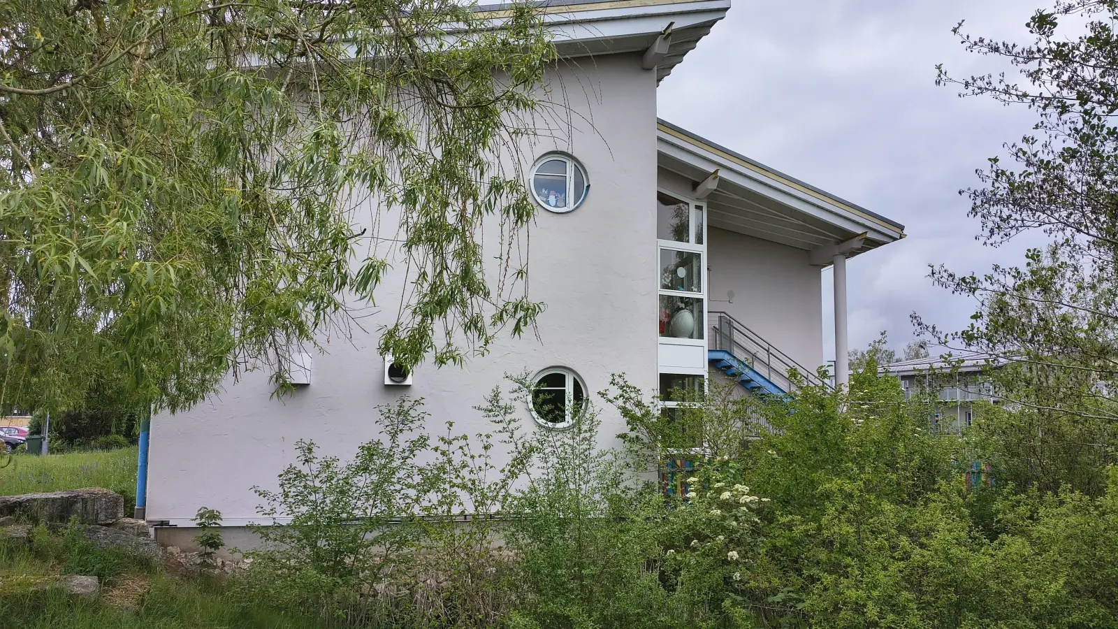 An die Ostseite der Merkendorfer Schule soll der Anbau gesetzt werden, um Platz für die Ganztagsbetreuung zu haben. Hinter den Büschen ist der naheliegende Kindergarten „Unterm Regenbogen” zu sehen.  (Foto: Robert Maurer)