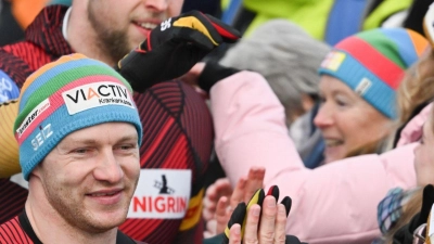 Francesco Friedrich (vorne l) und Alexander Schüller (hinten l) klatschen nach ihrem Sieg mit Fans ab. (Foto: Robert Michael/dpa)