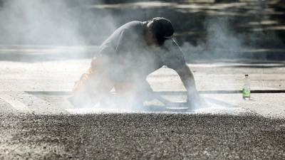 Ein Bauarbeiter repariert eine Straße in Berlin mit Bitumen, einem Bindemittel für Asphalt. (Symbolbild) (Foto: Wolfgang Kumm/dpa)