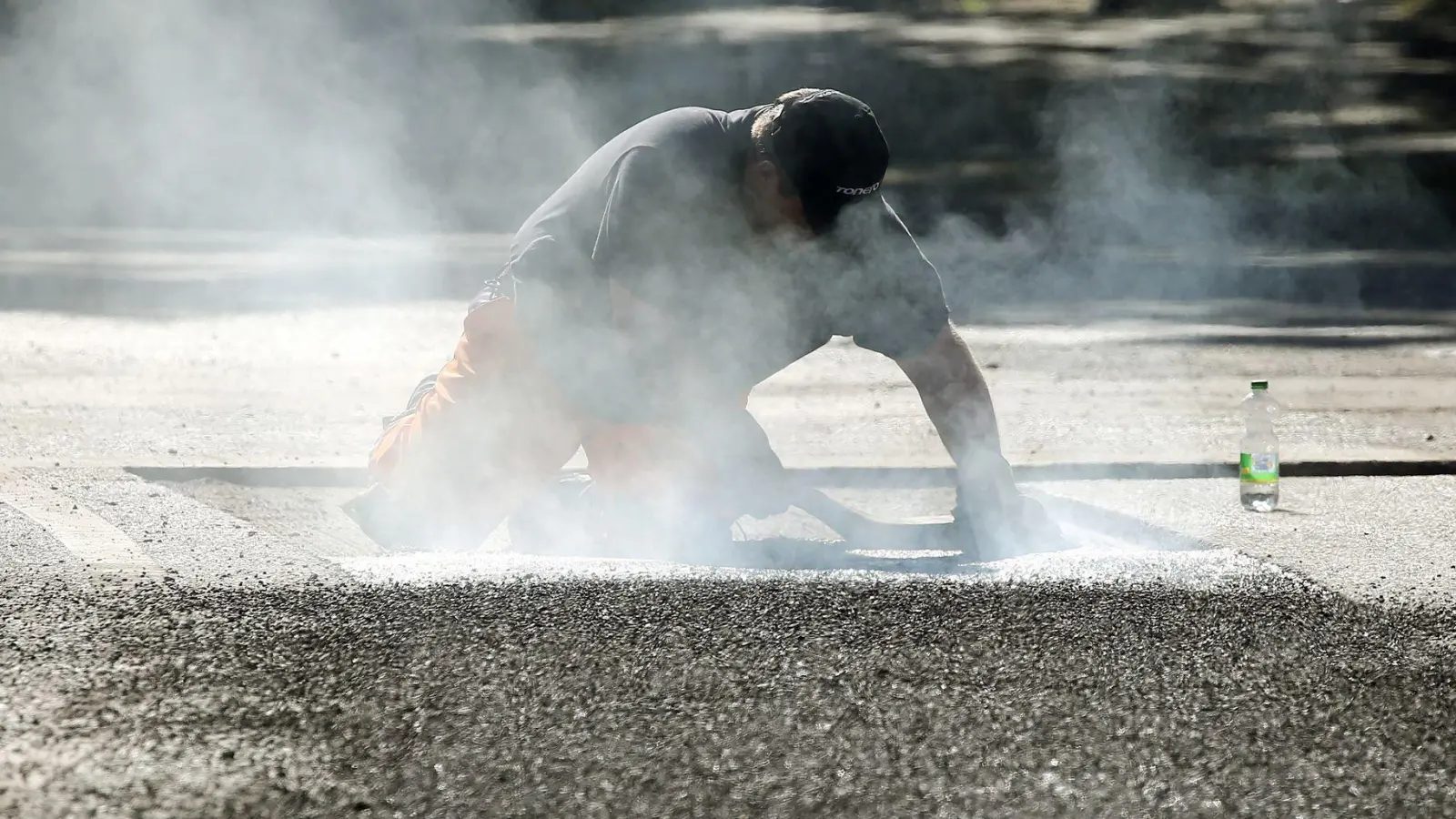 Ein Bauarbeiter repariert eine Straße in Berlin mit Bitumen, einem Bindemittel für Asphalt. (Symbolbild) (Foto: Wolfgang Kumm/dpa)