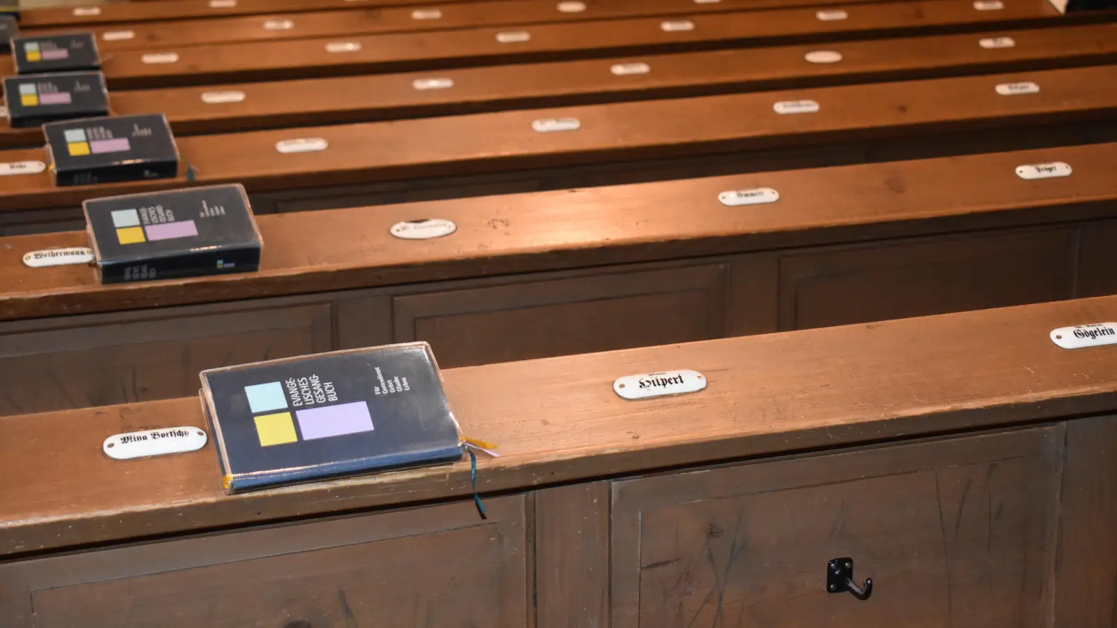 An den Bänken in der Stiftskirche finden sich nach wie vor weiße Schildchen mit den Namen der früheren Platzinhaber. Einst war dieser Brauch in evangelischen Kirchen in Franken weit verbreitet. (Foto: Erich Herrmann)