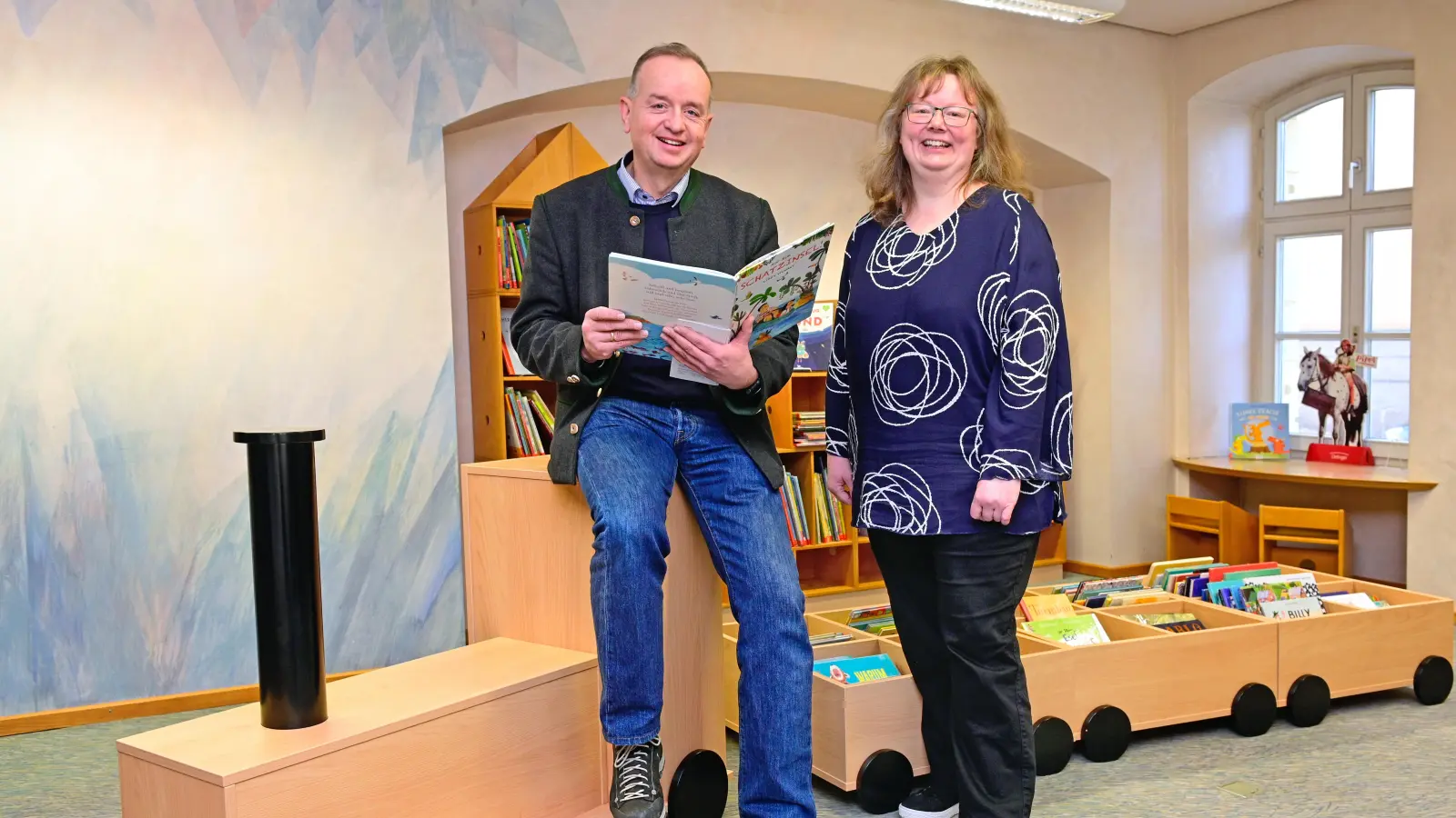 Oberbürgermeister Thomas Deffner und Bücherei-Leiterin Stephanie Heinrich in der Kinderabteilung der Stadtbücherei. Sie stellten das Jubiläums-Programm vor. (Foto: Jim Albright)