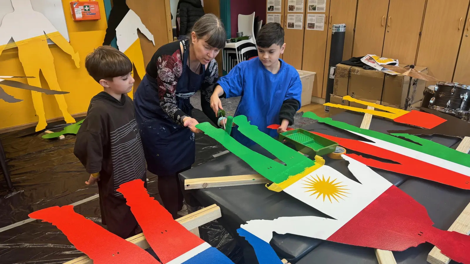 Die Künstlerin Patricia Tessitore hilft den Kindern bei der Gestaltung der Silhouetten. Die Farben sollen ganz exakt aufgetragen werden. (Foto: Lara Hausleitner)