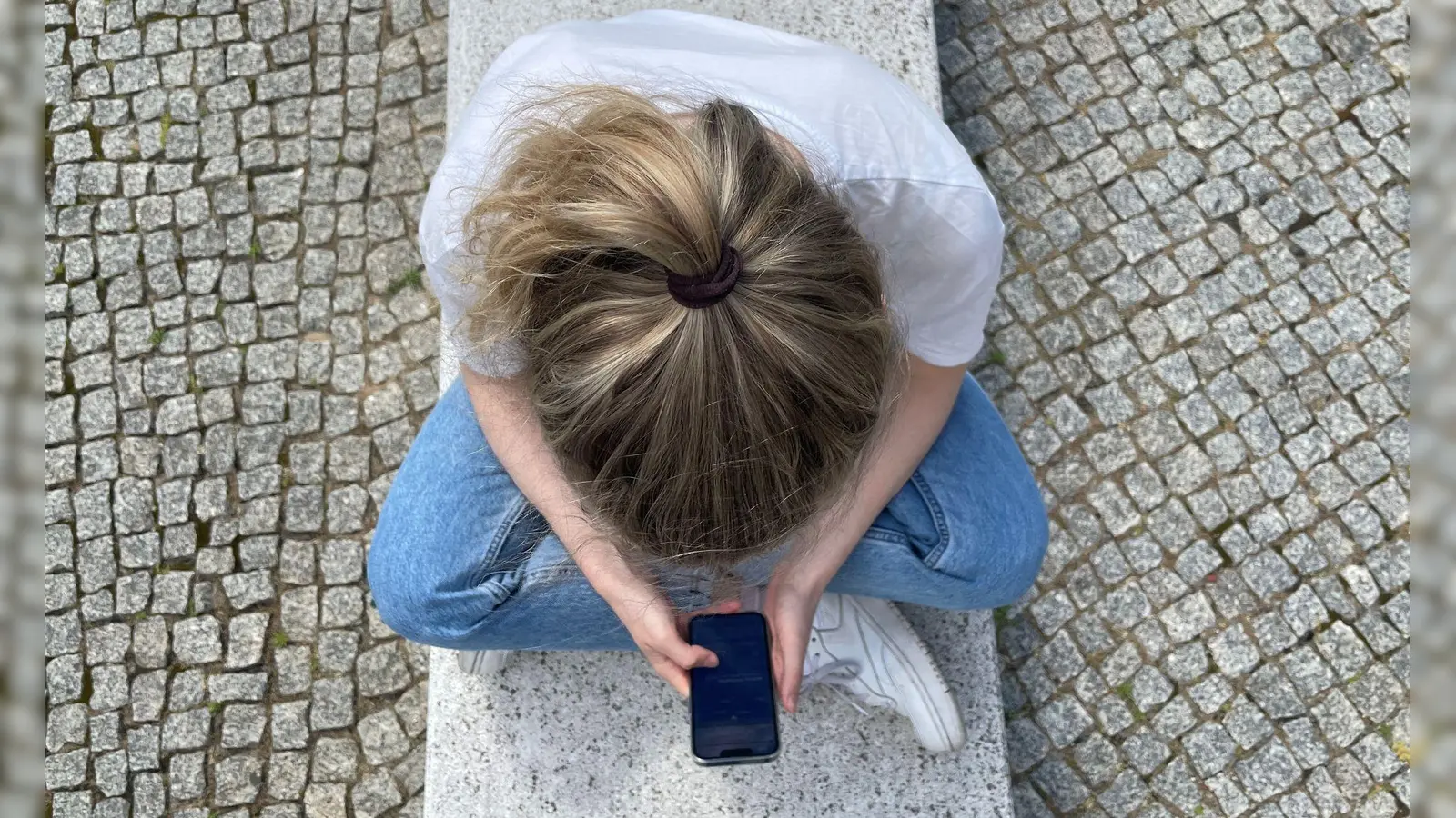 Typische Haltung in heutiger Zeit: mit gesenktem Kopf auf das Handy schauen. (Foto: Ricarda Dieckmann/dpa-tmn)