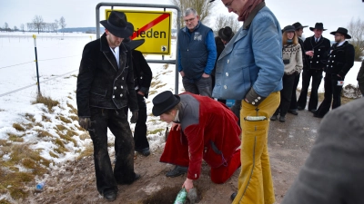 Begleiterin Fiona legte die Flaschen in das ausgebuddelte Loch, die Tim Oberfichtner (links) bei seiner Rückkehr nach mindestens drei Jahren wieder ausgraben und die halbe Flasche Schnaps als Dank für die erfolgreiche Walz mit Freunden austrinken wird. (Foto: Werner Wenk)