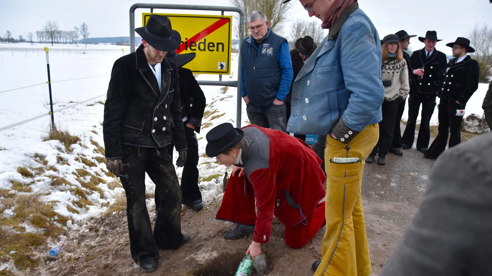 Begleiterin Fiona legte die Flaschen in das ausgebuddelte Loch, die Tim Oberfichtner (links) bei seiner Rückkehr nach mindestens drei Jahren wieder ausgraben und die halbe Flasche Schnaps als Dank für die erfolgreiche Walz mit Freunden austrinken wird. (Foto: Werner Wenk)