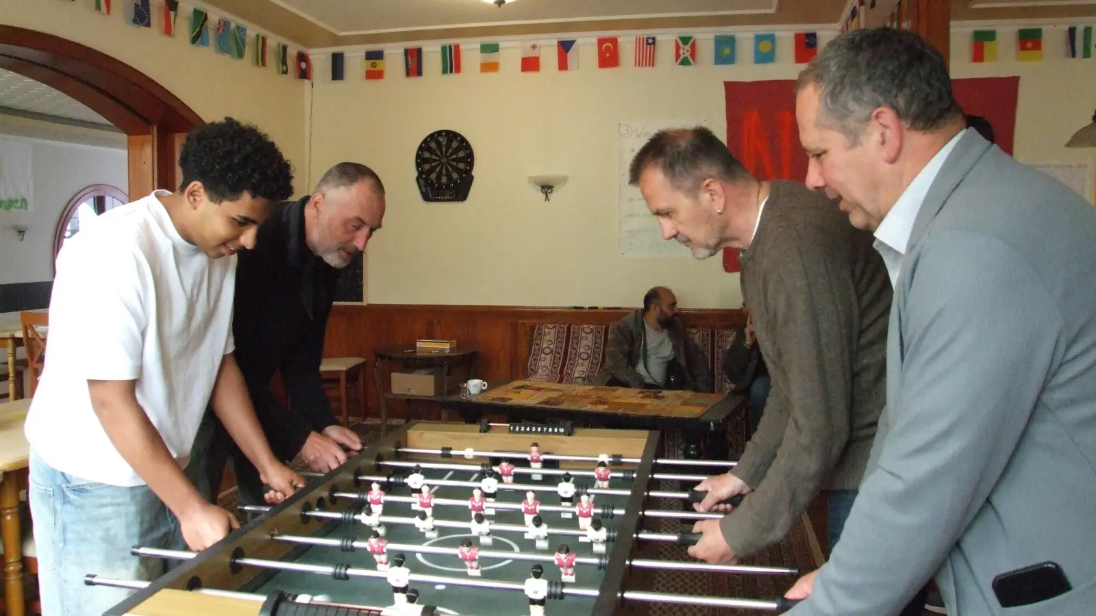Bei der offiziellen Eröffnung des Café Merhaba in den neuen Räumen spielten (von rechts) zweiter Bürgermeister Walter Soldner, der Referent für Menschen mit Behinderung und Integration, Stadtrat Thomas Ackermann, und der städtische Integrationsbeauftragte Peter Jüdt zusammen mit einem Gast gleich eine Partie Kicker. (Foto: Jasmin Kiendl)