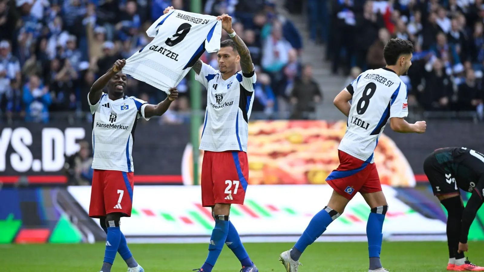 Gruß an Glatzel: Die HSV-Spieler Davie Selke (M) und Jean-Luc Dompe jubeln mit einem Trikot ihres verletzten Torjägers. (Foto: Gregor Fischer/dpa)