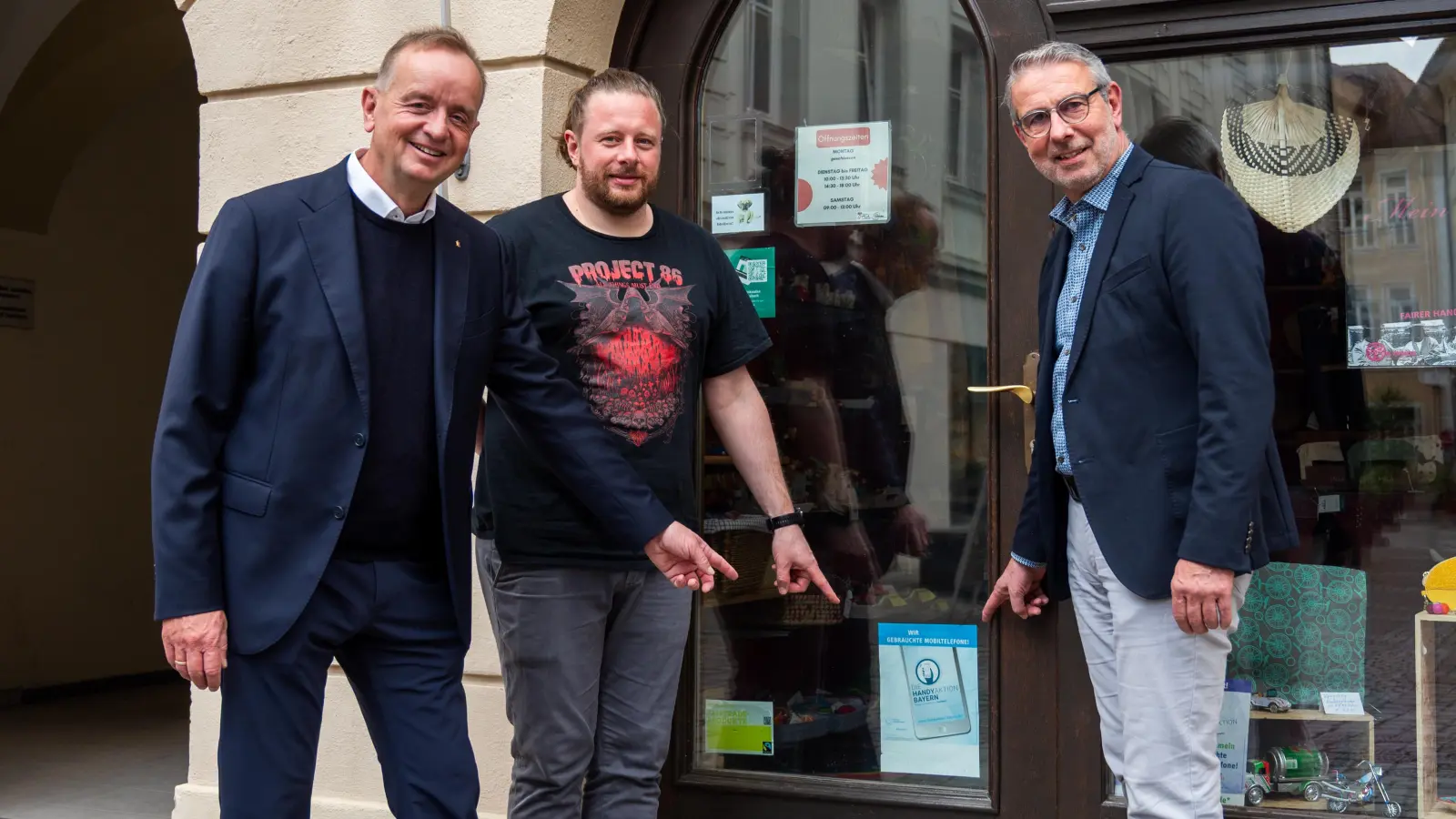 Auf das Zeichen der „Handy-Aktion“ im CVJM-Weltladen weisen Oberbürgermeister Thomas Deffner, Jan Schulte von dem Verein und Dekan Dr. Matthias Büttner hin (von links). (Foto: René Chlopotowski)