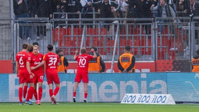 Die Spieler von Holstein Kiel freuen sich mit ihren Fans über einen unerwarteten Punkt bei Bayer Leverkusen. (Foto: Rolf Vennenbernd/dpa)