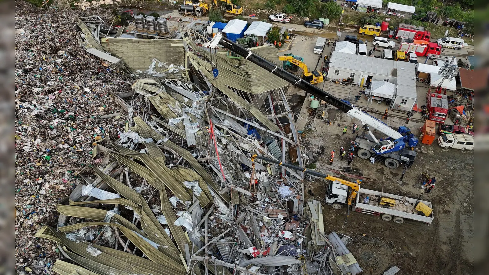 Die Einsatzkräfte suchen unter anderem mit einem Kran in den Abfall-Massen. (Foto: Jacqueline Hernandez/AP/dpa)