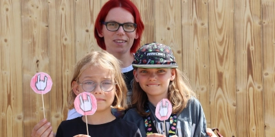 Mina (vorne rechts) verteilt ihre selbstgebastelten Pommesgabel-Schildchen an Metal-Fans. Sie ist gemeinsam mit ihrer Mutter Jessica Janitschek (hinten) und ihrer Schwester Lilly aus dem Odenwald angereist. (Foto: Antonia Müller)