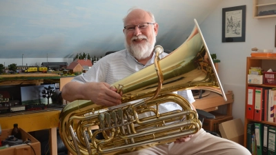 Auch die Tuba spielt Martin Schlenk. Der Pfarrer in Ruhestand liebt Blasmusik. Im Hintergrund ist sein zweites Hobby zu sehen. Die Modelleisenbahn, die viel Platz einnimmt, obwohl sie schon verkleinert werden musste. (Foto: Christa Frühwald)
