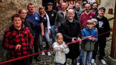 Für die Einweihungszeremonie war auch ein rotes Band gespannt worden. Durchschneiden durften es zusammen mit Oberbürgermeister Dr. Markus Naser die Geschwister Maja und Leo Kölle. Im Hintergrund ist die Beutelschneider-Gruppe zu sehen, die den gesanglichen Part übernahm. (Foto: Jürgen Binder)
