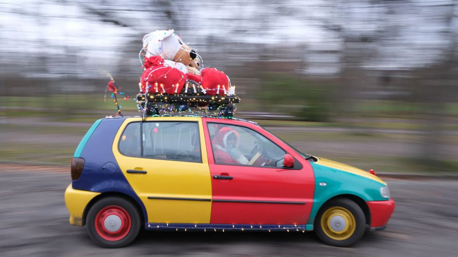 Ein Auto vom Typ Volkswagen Polo in der Edition Harlekin aus dem Jahr 1996 fährt weihnachtlich dekoriert durch Leipzig.  (Foto: Sebastian Willnow/dpa)