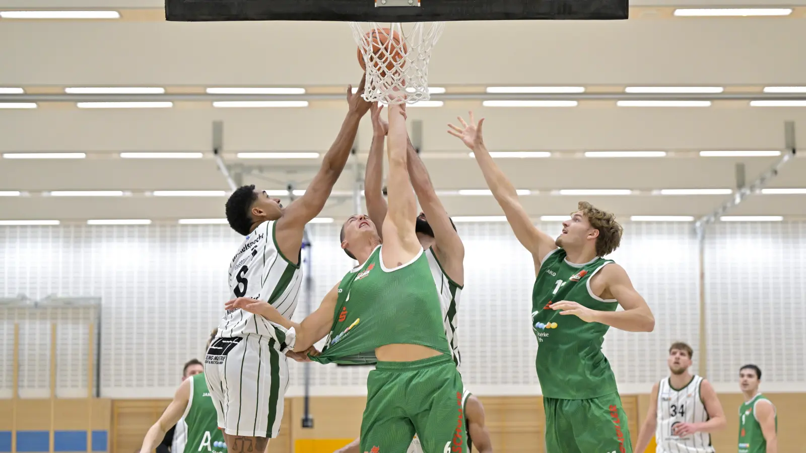 Die Neustädter Aaron Winkelspecht (links) und Nedal Jenniat (verdeckt in der Mitte) strecken sich gegen David Kurpiela und Pablo Schmidt (in grün von links) vergeblich, am Ende gewann Ansbach mit 79:55. (Foto: Martin Rügner)