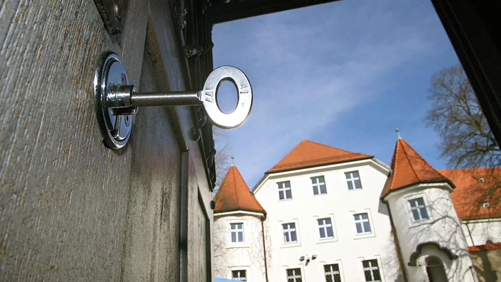 Im Schloss der geöffneten Türe des Eingangsbereiches der Justizvollzugsanstalt in Aichach steckt ein Schlüssel. Ein Beamter des Gefängnisses wurde nun zu einer Geldstrafe verurteilt, weil er einen Insassen geschlagen hatte. (Archivbild-Illustration) (Foto: Karl-Josef Hildenbrand/dpa)