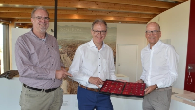 Einblicke in den Münzkoffer gewährte Museumsleiter Dr. Matthias Pausch (links) bei der Spendenübergabe der Sparkassenstiftung Ansbach durch Werner Frieß (rechts) an den Vorsitzenden des Fördervereins Römerpark Ruffenhofen, Bernd Großmann (Mitte). (Foto: Peter Tippl)