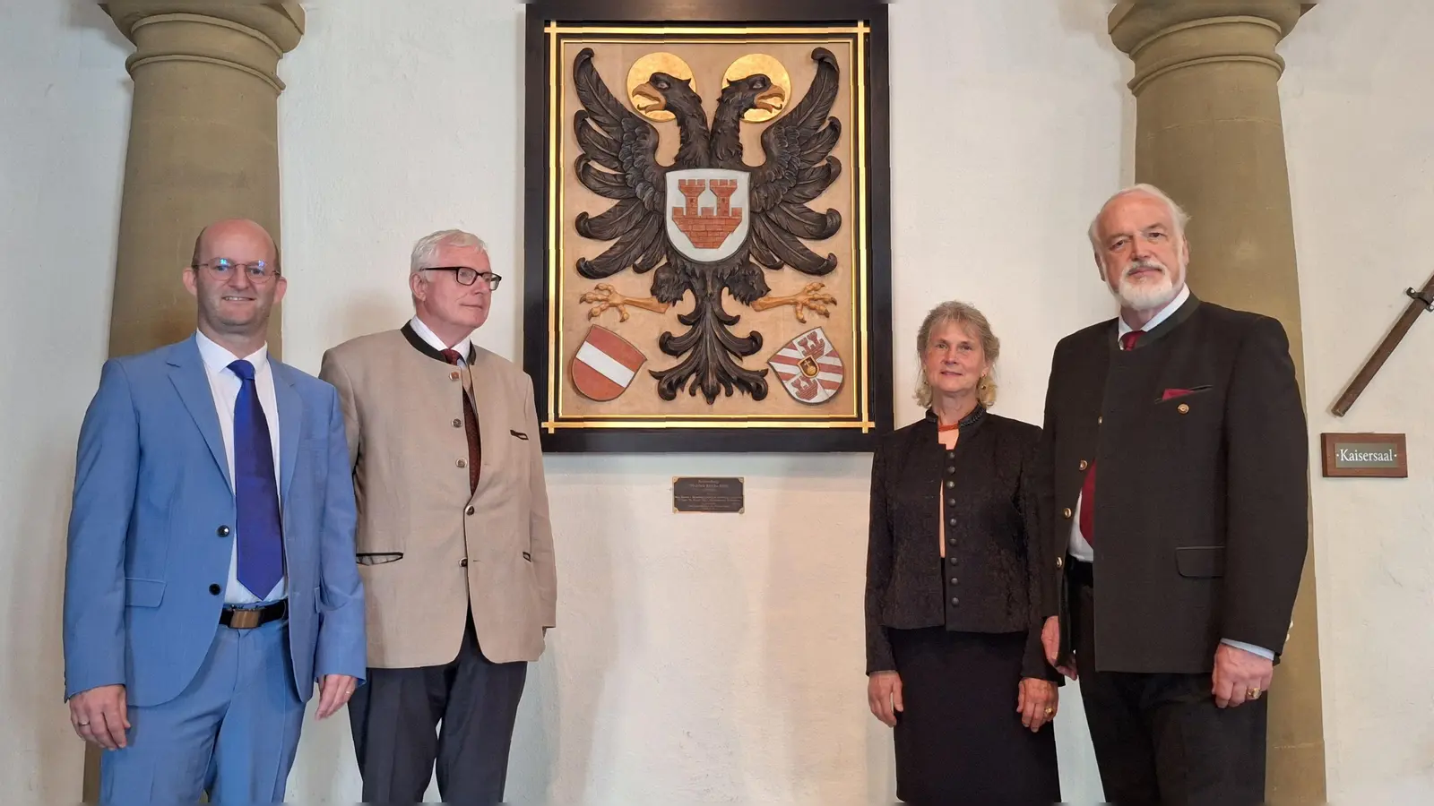 Die Wappentafel hat ihren festen Platz im Foyer vor dem Kaisersaal. Das Foto zeigt (von rechts) Dr. Egon Freiherr von Ellrichshausen-Rothenburg, dessen Ehefrau Dr. Margit Freifrau von Ellrichshausen-Rothenburg, Erzherzog Markus von Habsburg-Lothringen und Oberbürgermeister Dr. Markus Naser vor dem Schild, das ein Geschenk zur 750-Jahr-Feier der Verleihung des Freiheitsprivilegs war. (Foto: Jürgen Binder)