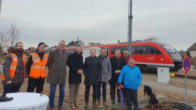 Beim Pressetermin passiert ein Zug den Bahnübergang in der Hohenecker Straße in Ipsheim. Über die Schranken freuen sich (von links): Ismail Ataman, Richard Thöns (beide DB), Stefan Schmidt, Dr. Christian von Dobschütz, Hans Herold, der CSU-Landtagsabgeordnete Werner Stieglitz, der SPD-Bundestagsabgeordnete Carsten Träger, SPD-Kreisrat Bernhard Schurz sowie der SPD-Landtagsabgeordnete Harry Scheuenstuhl. (Foto: Anna Franck)