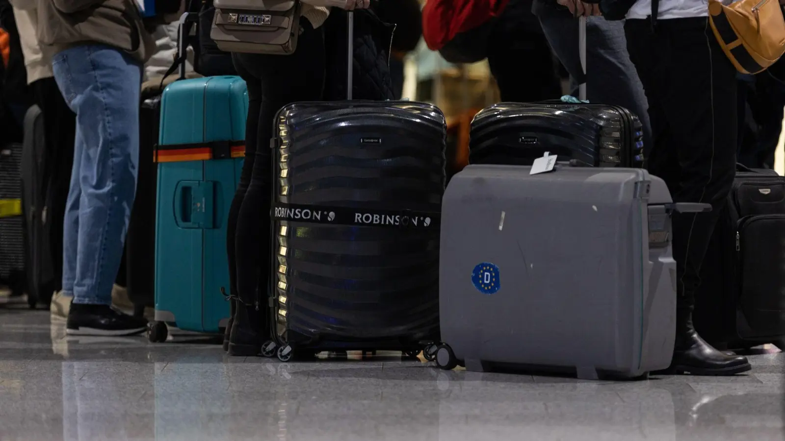 Passagiere mit Koffern warten am Check-In Schalter am Frankfurter Flughafen. (Foto: Hannes P. Albert/dpa)