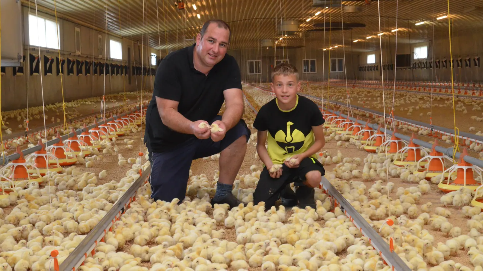 Thomas Ehrenbrand (mit Sohn Theo) möchte mit Transparenz gegen Vorurteile vorgehen. Wer seine bestehenden Ställe besichtigt, sieht freilaufende Küken. Der geplante Stall soll den Tieren durch einen Außenbereich mit Frischluft und Tageslicht mehr Lebensqualität bieten. (Foto: Yvonne Neckermann)