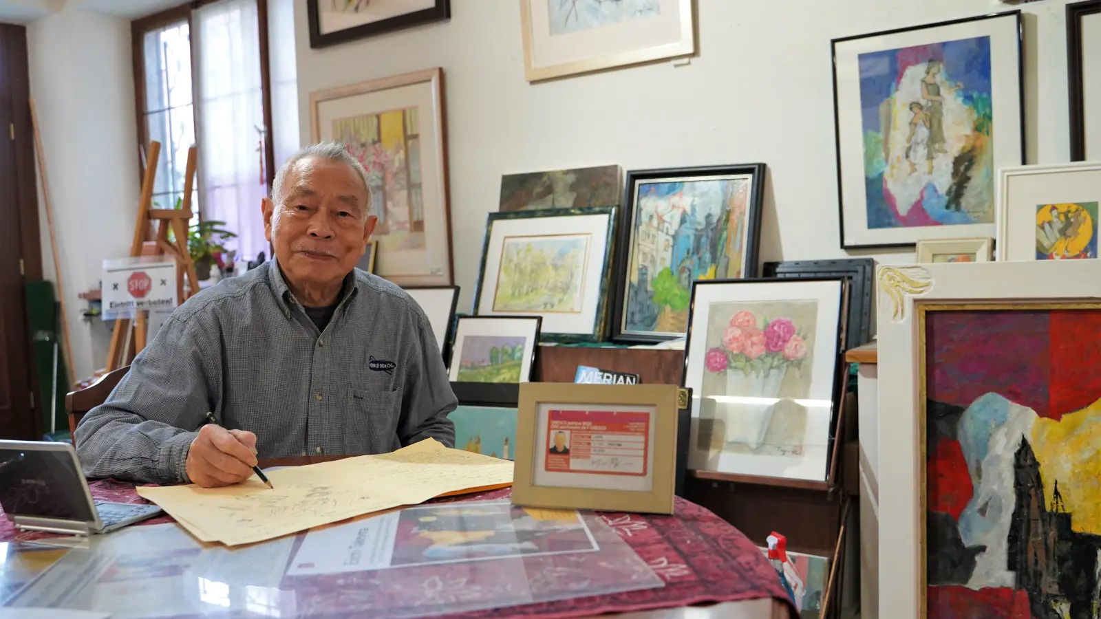 In seinem Atelier ist Eiichi Takeyama umrahmt von zahlreichen seiner Werke. Wenn ihm die deutschen Wörter fehlen, zeichnet er das, was er sagen will, einfach auf ein Blatt Papier.  (Foto: Simone Hedler)