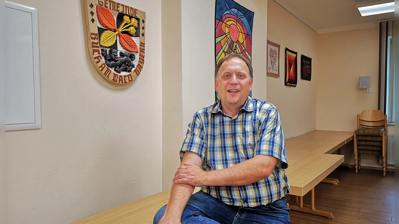 Mit seiner Rolle als ehrenamtlicher Bürgermeister von Buch am Wald kommt Hartmut Buckel gut klar. Das Foto zeigt ihn im Sitzungssaal neben dem Gemeindewappen. (Foto: Jürgen Binder)