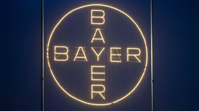 Das Bayer-Kreuz, das Logo des Unternehmens, leuchtet auf dem Werksgelände von Bayer in Leverkusen. (Foto: Thomas Banneyer/dpa)