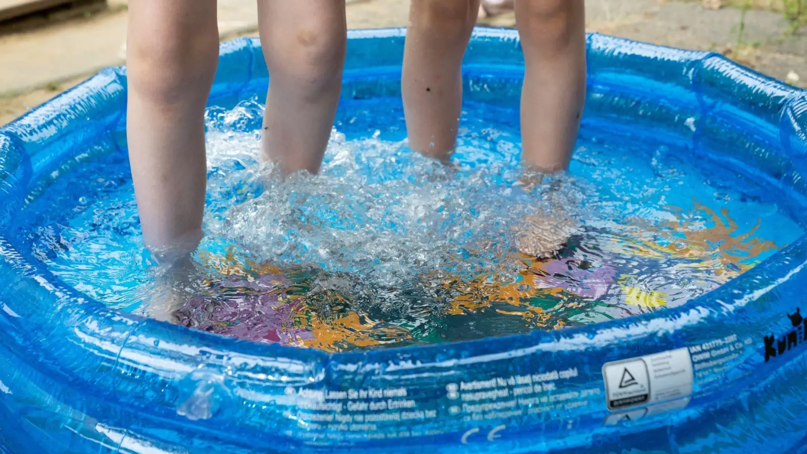 Kinder stehen in einem Planschbecken. (Foto: Sebastian Kahnert/dpa)