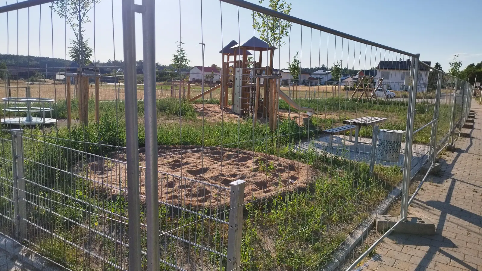 Weil der Rasen noch anwachsen soll, bleibt der neue Spielplatz in Meinhardswinden geschlossen. Das Grün auf der Fläche sieht allerdings weniger nach Rasen als nach Unkraut aus. (Foto: Robert Maurer)