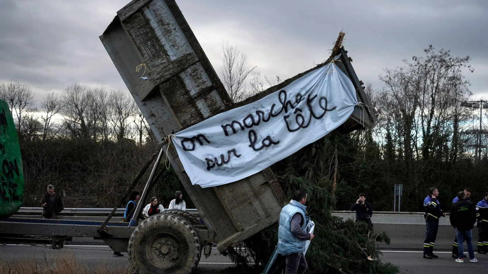 Landwirte kippen Zweige und Äste auf die Fahrbahn, während sie eine Autobahn in der Nähe von Lyon blockieren. (Foto: Laurent Cipriani/AP/dpa)