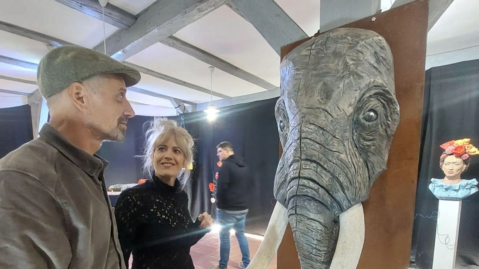 Laura Bräuninger mit einem Vernissagengast: Der von ihr mit der Motorsäge gestaltete Elefantenkopf ist mittlerweile schon eine Art Wahrzeichen der Künstlerin.  (Foto: Sandra Buchwald)