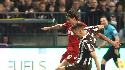 Die aus Sicht von Alexander Blessin strittige Szene vor dem Strafstoß: Kölns Jakub Kaminski (M,) und Karol Mets (FC St. Pauli) kämpfen um den Ball. (Foto: Christian Charisius/dpa)