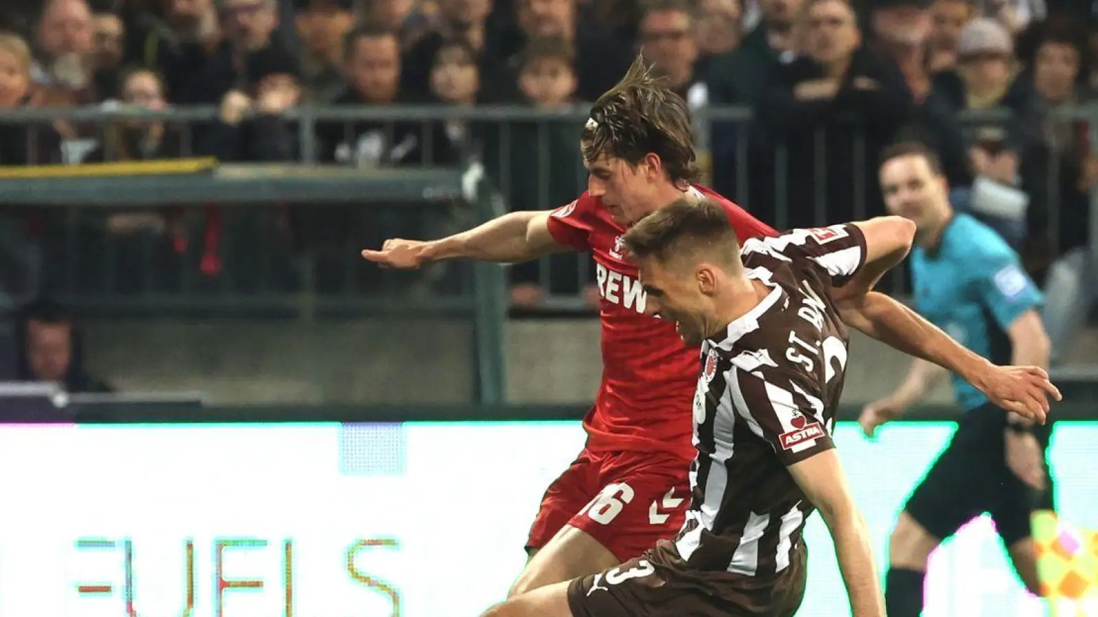 Die aus Sicht von Alexander Blessin strittige Szene vor dem Strafstoß: Kölns Jakub Kaminski (M,) und Karol Mets (FC St. Pauli) kämpfen um den Ball. (Foto: Christian Charisius/dpa)