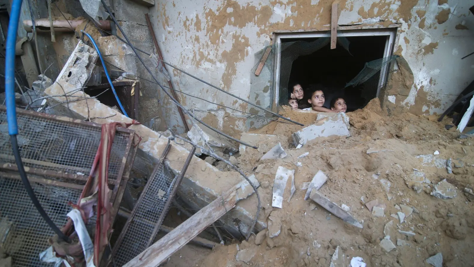 Palästinensische Kinder schauen in Rafah im Süden des Gazastreifens aus einem Fenster, das bei israelischen Luftangriffen zerstört wurde. (Foto: Hatem Ali/AP/dpa)