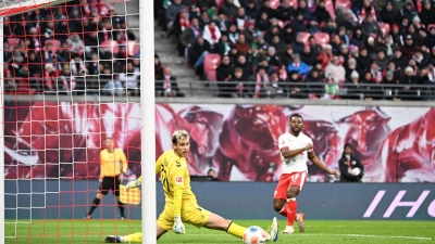 Bremens Torwart Mio Backhaus (l, Werder Bremen) und Ridle Baku (RB&nbsp;Leipzig) schauen dem Ball hinterher. Backhaus verhinderte mit seinen Paraden einen frühen Rückstand der Gäste in Leipzig. (Foto: Jennifer Brückner/dpa)