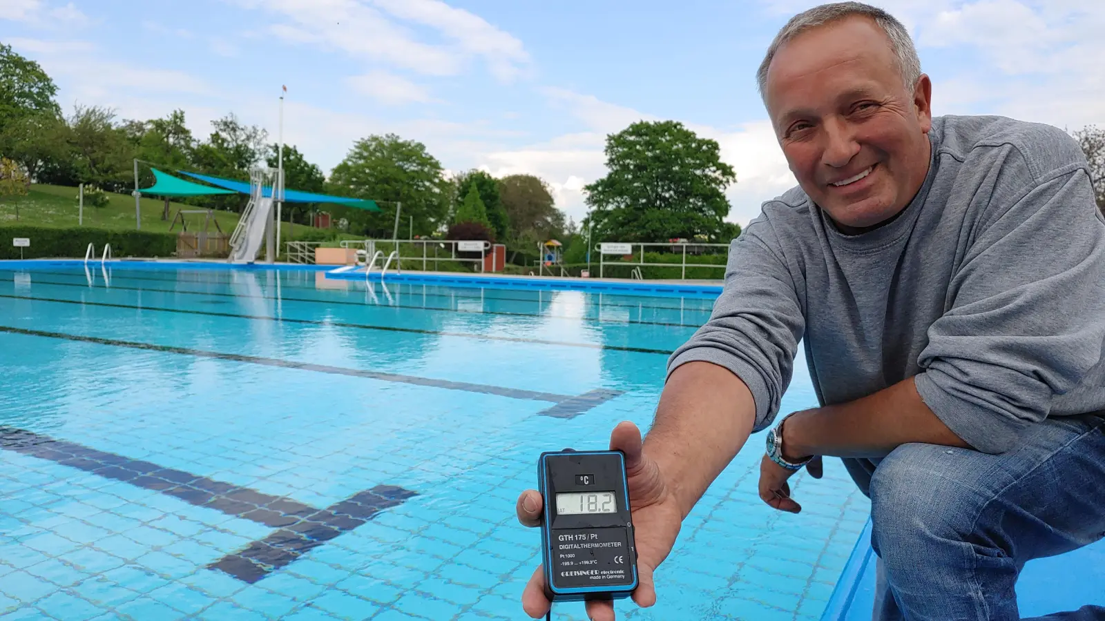 Freibad-Chef Stefan Keller misst vor dem Start noch einmal die Temperatur im Burgbernheimer Nichtschwimmer-Becken: 18,2 Grad Celsius zeigt das Thermometer an. (Foto: Katrin Merklein)