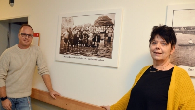 Patrick Seybold und Izabela Rosinski vor ihrem Lieblingsbild im Uehlfelder Seniorencentrum: dem schweren Hochwasser am unteren Torhaus im Jahr 1941, bei dem die Anwohnerinnen und Anwohner zusammenstanden. (Foto: Johannes Zimmermann)