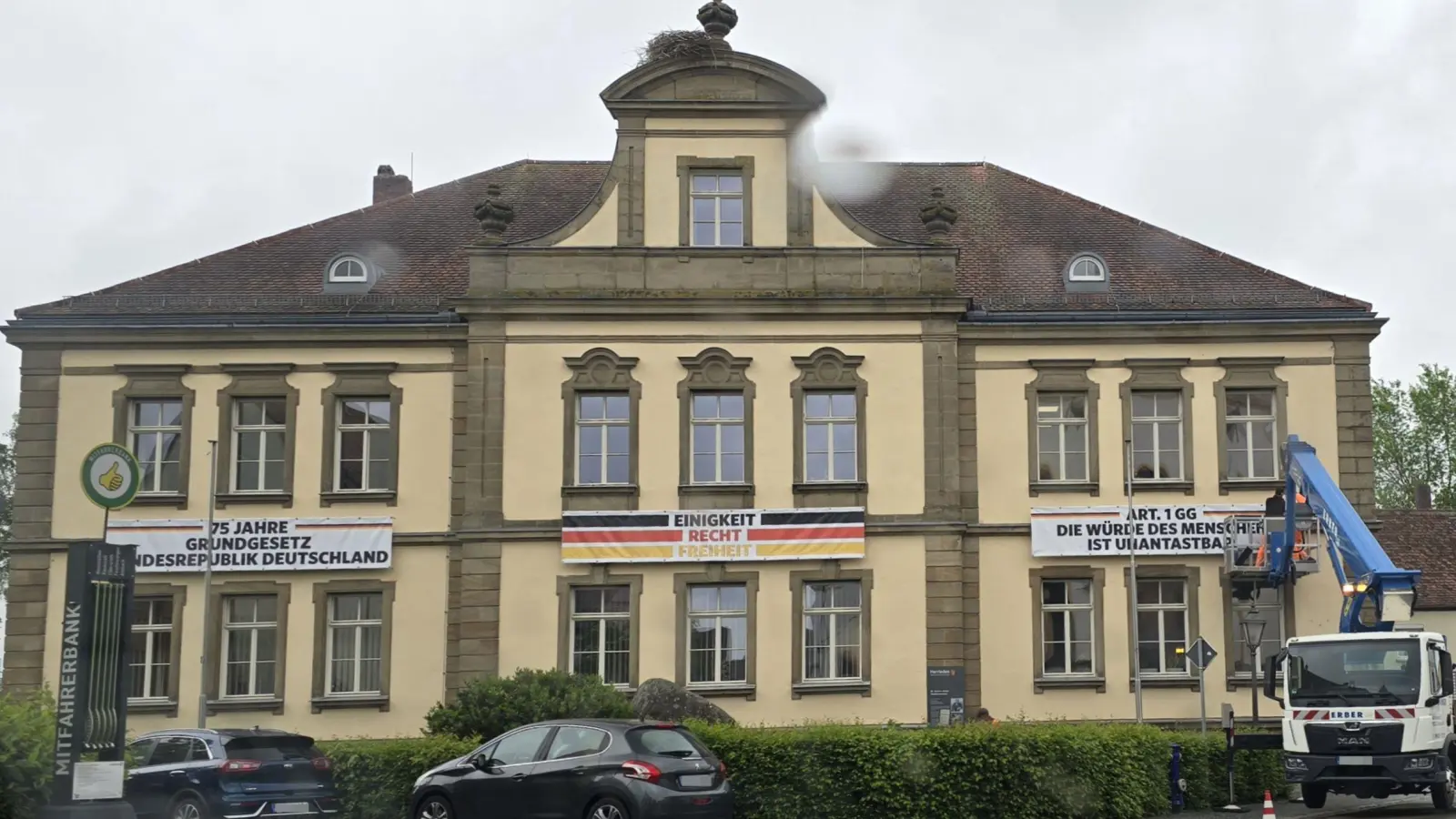 Drei Banner wurden jetzt mit Hilfe einer Hebebühne an der Fassade des Herriedener Rathauses angebracht. Sie erinnern an das Inkrafttreten des Grundgesetzes vor 75 Jahren. Geplant ist, die Zitate von Passagen der Verfassungsordnung von Zeit zu Zeit zu wechseln. (Foto: Stadt Herrieden/Anja Schwander)