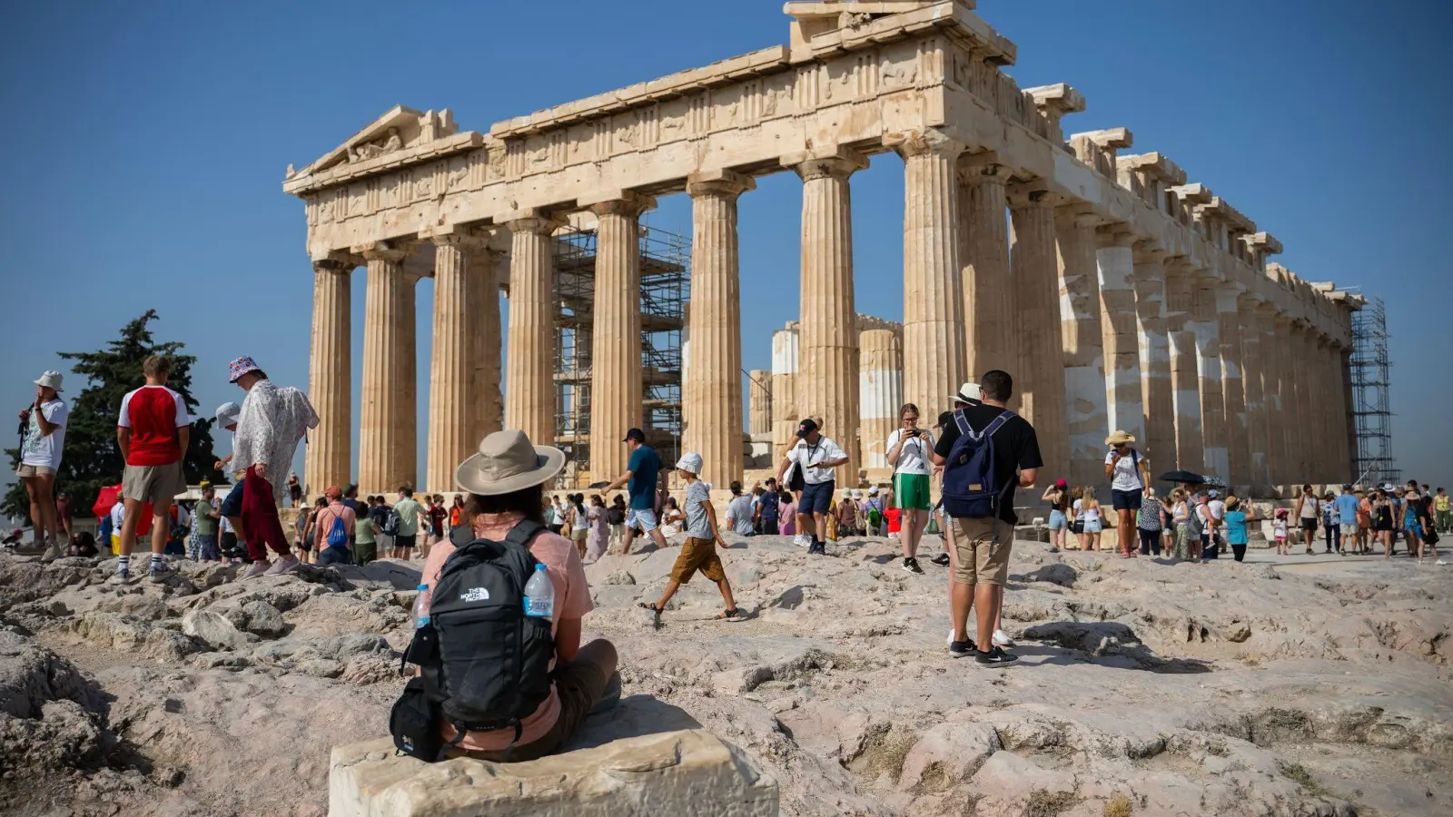 Touristen an einem heißen Tag bei ihrem Besuch des Parthenon-Tempels auf dem Akropolis-Hügel in Athen. (Foto: Angelos Tzortzinis/dpa)