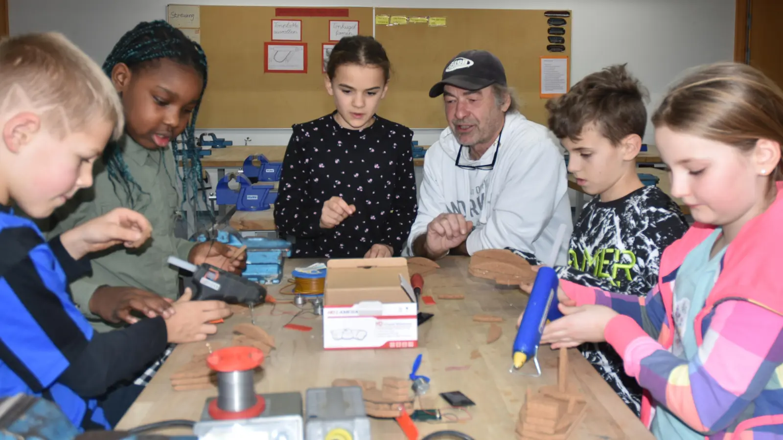 Johannes, Elisia, Hanna sowie Bastian und Antonia (von links) sind schwer mit dem Basteln und Zusammenlöten eines Minischiffleins beschäftigt. Rudi Benedikt weist sie an. (Foto: Anita Dlugoß)