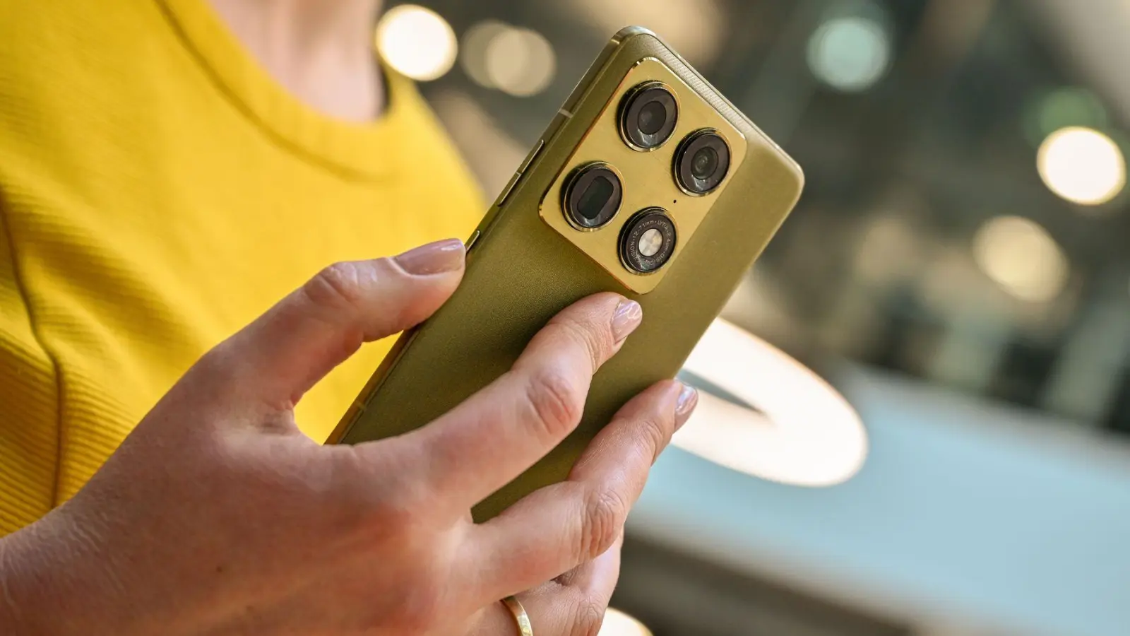 Nicht nur Technik, auch Look: Martini Olive heißt die Pantone-Farbe des Motorola Signature, die sich gut mit dem Gelb des Oberteils verträgt.  (Foto: Nico Tapia/dpa-tmn)