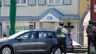 Polizeikräfte halten sich rund um die Bankfiliale bereit.  (Foto: Thomas Frey/dpa)