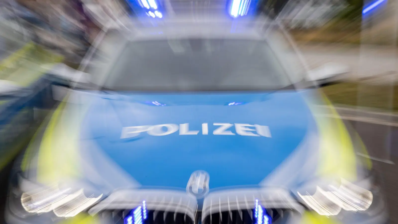 Ein Streifenwagen der Polizei mit eingeschaltetem Blaulicht. (Foto: Daniel Karmann/dpa/Symbolbild)